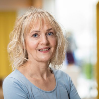 Sonja Wahl, Verwaltungsangestellte bei disana in hellblauem Longsleeve vor unscharfem Hintergrund lächelt in die Kamera.