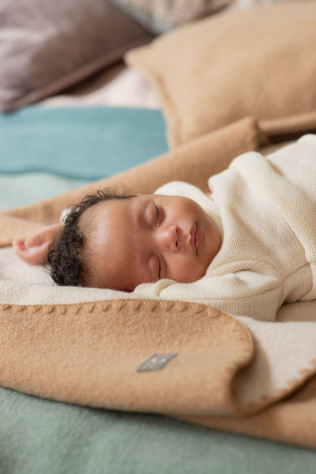 Baby mit hellbraunem Hautton im disana Baby-Pullover, Natur, auf Doubleface-Babydecke in Karamell-Natur schlafend