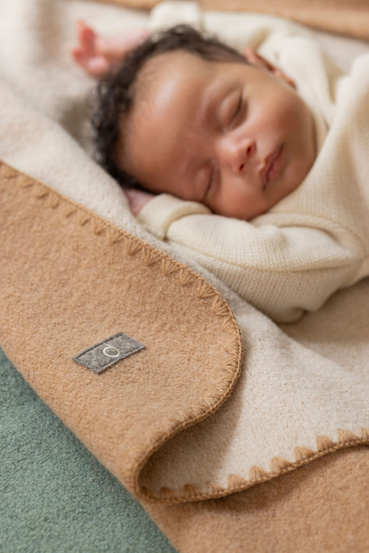 Baby mit hellbraunem Hautton im disana Baby-Pullover, Natur, auf Doubleface-Babydecke in Karamell-Natur schlafend